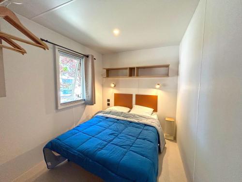 Un pequeño dormitorio con una cama azul y una ventana en Camping Saint-Cyprien, en Saint-Cyprien