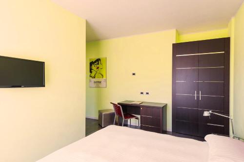 a bedroom with a bed and a desk and a tv at T'AMI Hotel Resort Spa in Selvino