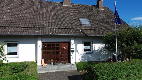a white house with a brown door and a flag at Ferienwohnung Schäfer in Vöhl