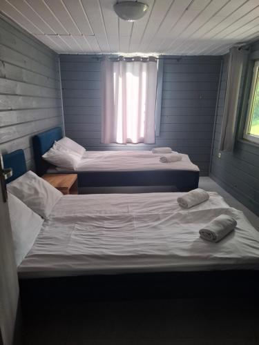 two beds in a small room with a window at Domek na pensjonatowej 8 in Augustów