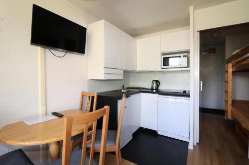 Il comprend une petite cuisine avec une table en bois et des placards blancs. dans l'établissement Résidence Home Club - Studio avec vue imprenable retour ski aux pieds MAE-3904, à Tignes