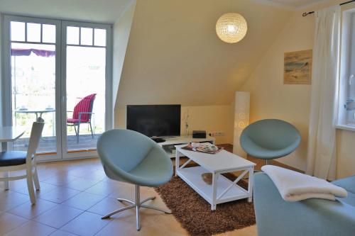 a living room with two chairs and a tv at Exkl Strandappartement Parkstr 5 mit Meerblick u Kamin in Börgerende-Rethwisch