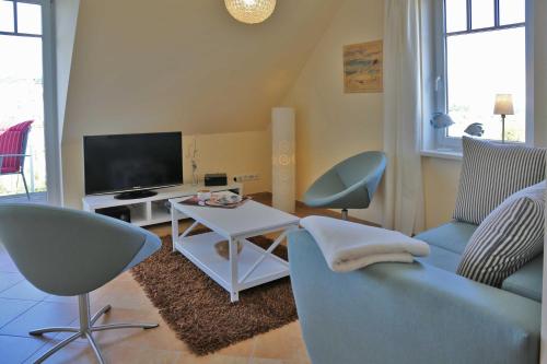 a living room with a couch and chairs and a tv at Exkl Strandappartement Parkstr 5 mit Meerblick u Kamin in Börgerende-Rethwisch
