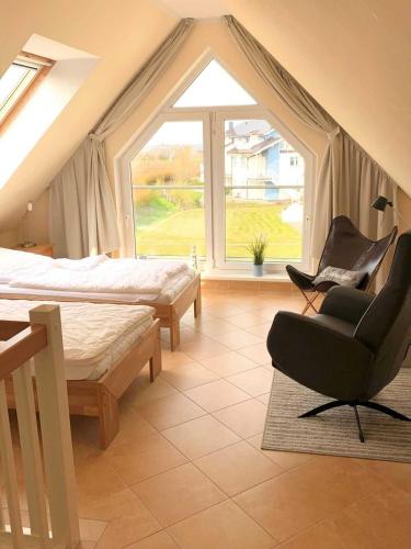 a bedroom with a bed and a chair and a window at Exkl Strandappartement Parkstr 5 mit Meerblick u Kamin in Börgerende-Rethwisch