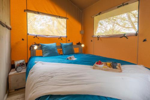 a bedroom with a large bed with blue and orange walls at Camping Saint-Sozy in Saint-Sozy