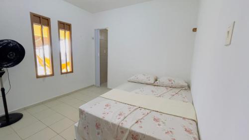 a white bedroom with a bed and two windows at Casa de Veraneio na Praia in Extremóz