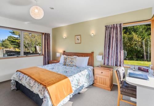 a bedroom with a bed and a desk and window at Woodland Glen Lodge B&B in Hokitika