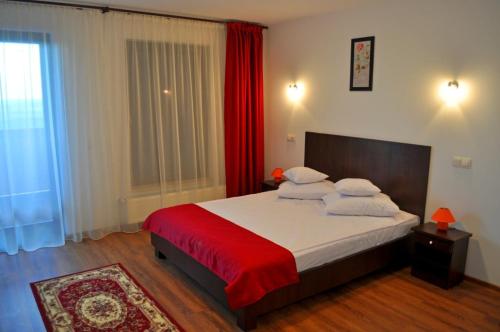 a bedroom with a large bed with red curtains at Pensiunea Cheile Apusenilor Cheile Turzii near Turda in Sănduleşti