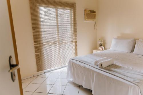 a bedroom with a white bed and a window at Recanto dos Corais - Praia do Gravatá - Navegantes in Navegantes