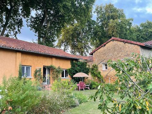 a house with a table and an umbrella in the yard at Le Petit Basket in Castex