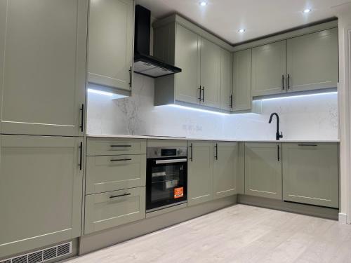 a kitchen with white cabinets and an oven at Rose Mews, Newly Refurbed Modern Interior with Garden in Edmonton