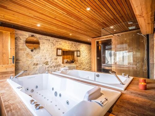 a large white tub in a bathroom with a stone wall at Camping Saint-Sozy in Saint-Sozy