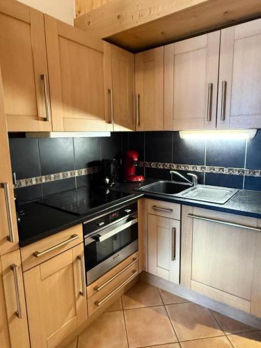 une cuisine avec des armoires en bois et un four à plaques de cuisson dans l'établissement Résidence L'oree Des Neiges - Appartement de 6 personnes confort un départ skis aux pieds et situé proche du centre de la station de Vallandry MAE-3711, à Peisey-Nancroix