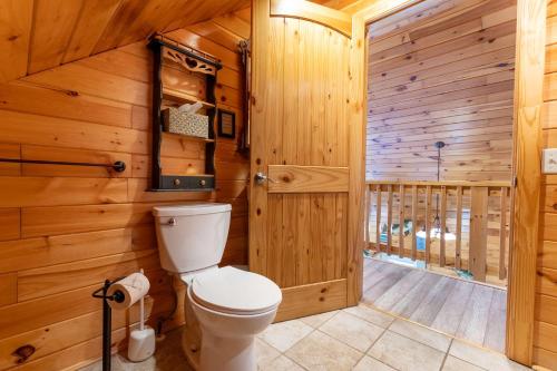 a bathroom with a toilet and wooden walls at Fish Tales Cabin with a private hot tub in Bryant