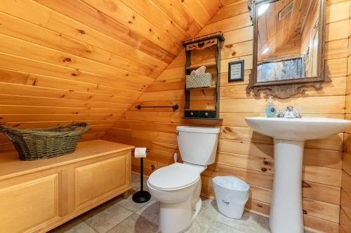 a bathroom with a toilet and a sink in a log cabin at Fish Tales Cabin with a private hot tub in Bryant