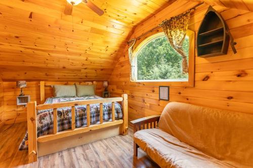 a log cabin bedroom with a bed and a window at Fish Tales Cabin with a private hot tub in Bryant