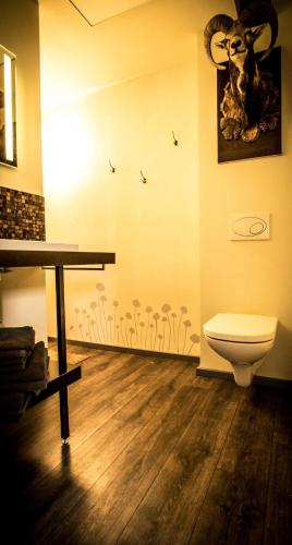 a bathroom with a toilet and a picture of a ram on the wall at Chalet Sch l afbock in Priesteblich