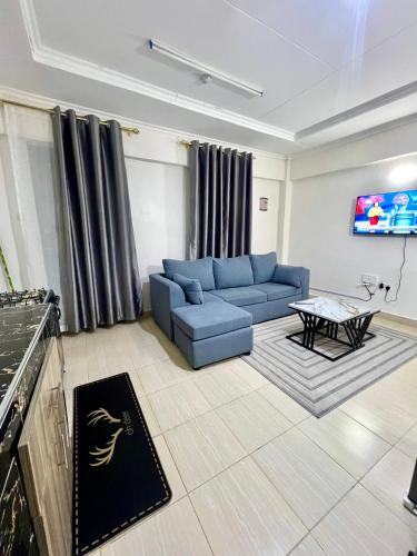 a living room with a blue couch and a table at Elite suite 1bedroom in Busia