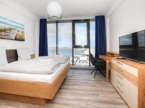 a bedroom with a bed and a television and a desk at Ohlerich Speicher App_ 46 in Wismar