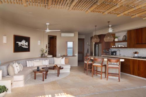 a living room with a white couch and a kitchen at Punta Majahua by PRC Hospitality in La Majahua