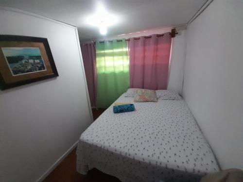 a small bedroom with a bed with rainbow curtains at Hotel Victoria s Beach House in Roatan
