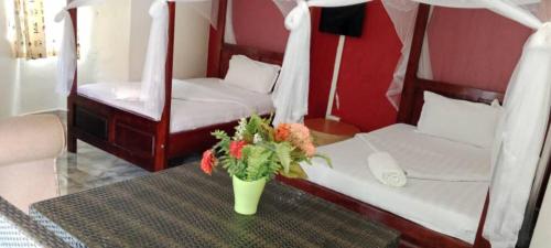 a vase with flowers on a table in a room at Gorilla African Guest House in Entebbe