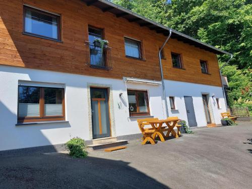 a building with two picnic tables in front of it at Ferienwohnung Oberschledorner Wald in Medebach
