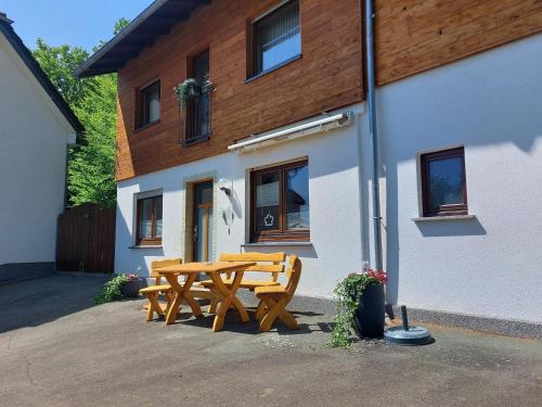 a wooden picnic table in front of a building at Ferienwohnung Oberschledorner Wald in Medebach