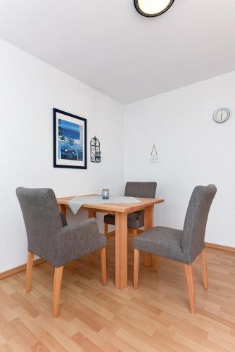 a dining room with a wooden table and two chairs at Haus Hafenblick in Bensersiel