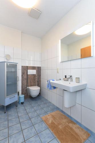 a white bathroom with a sink and a toilet at Haus Hafenblick in Bensersiel