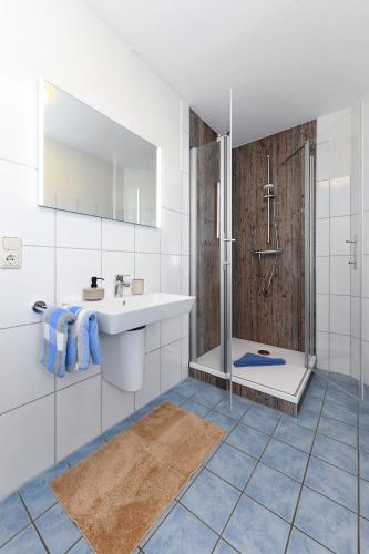 a white bathroom with a sink and a shower at Haus Hafenblick in Bensersiel