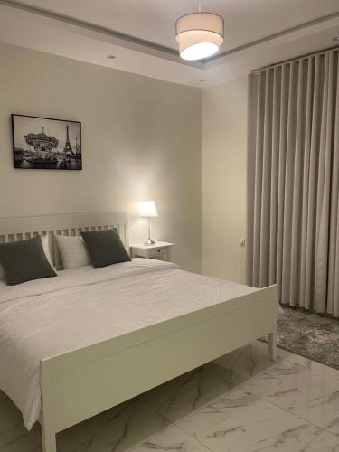 a white bedroom with a large bed and a window at شقة الردف in Taif