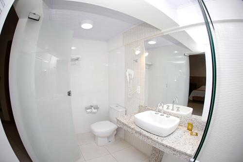 a white bathroom with a sink and a toilet at Luz Hotel Pato Branco in Pato Branco