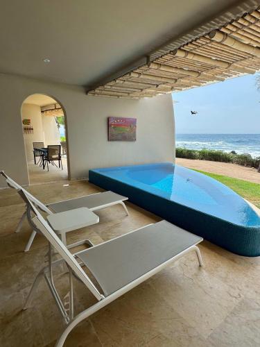 a large swimming pool in a room with a table and chairs at Punta Majahua by PRC Hospitality in La Majahua