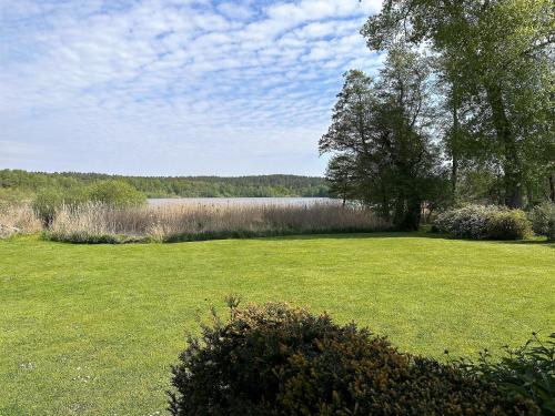 滨湖克拉科Ferienhaus am See auf großem Grundstück, Kaminofen的一片大片草地,有湖面背景