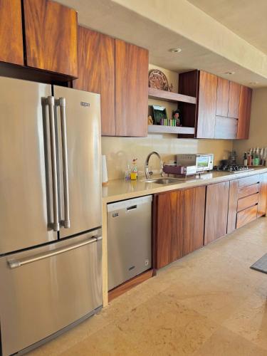 a kitchen with wooden cabinets and a stainless steel refrigerator at Punta Majahua by PRC Hospitality in La Majahua