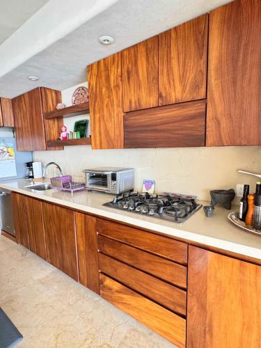 a kitchen with wooden cabinets and a stove top oven at Punta Majahua by PRC Hospitality in La Majahua