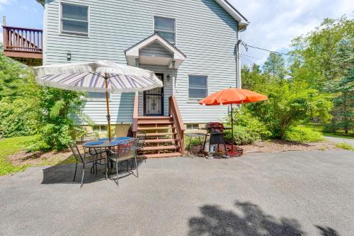 a house with two umbrellas and a table and chairs at 1 Mi to Hunter Mtn Cozy Unit on 6-Acre Property! in Hunter