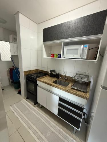 a small kitchen with a sink and a microwave at Apartamento em Ubatuba! A 100m da praia das Toninhas! in Ubatuba