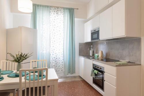 a kitchen with white cabinets and a table and a dining room at Sea Lily in Lido di Ostia