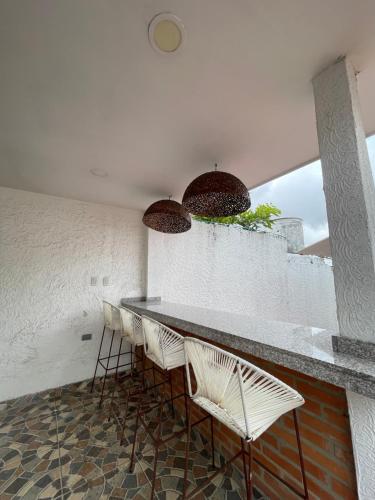 a bar with white chairs and a counter at Baranoa House in Barranquilla