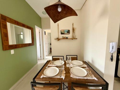 a dining room with a table with plates on it at Apartamento em Ubatuba! A 100m da praia das Toninhas! in Ubatuba