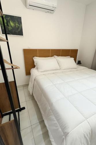 Cama blanca en habitación con escalera en Flat Intermares, en Cabedelo
