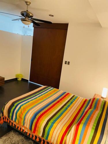 a colorful striped bed in a room with a brown door at Northtown San Ramón in Mérida