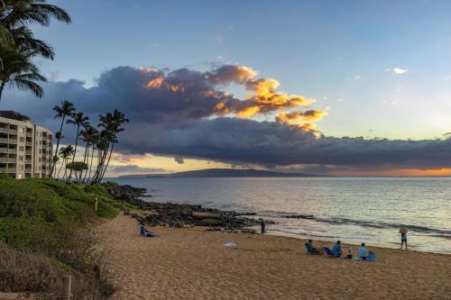 a group of people sitting on the beach at sunset at WorldMark Kihei in Kihei
