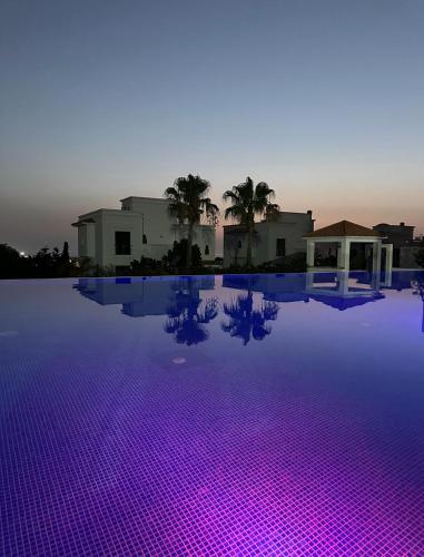 a swimming pool with purple lights in the water at Asilah Prestige -Vue Mer -Haut Standing - Piscines- Plage à 5 minute - Garage privée - Navette in Asilah