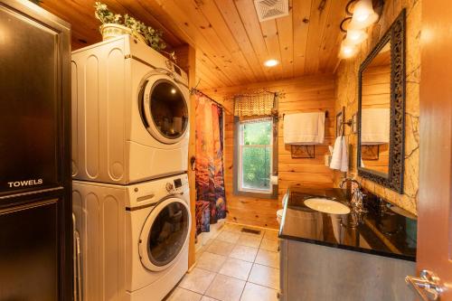 a bathroom with a washer and dryer in a log cabin at Hoot Owl with a private hot tub in Bryant