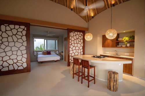 a kitchen with a island and a bedroom with a bed at Punta Majahua by PRC Hospitality in La Majahua