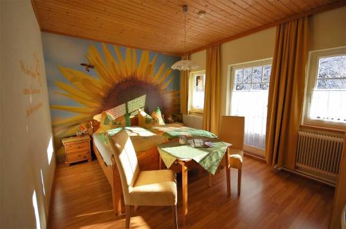 a dining room with a table and a sunflower painting on the wall at Ferienhaus Tschernitz in Pruggern