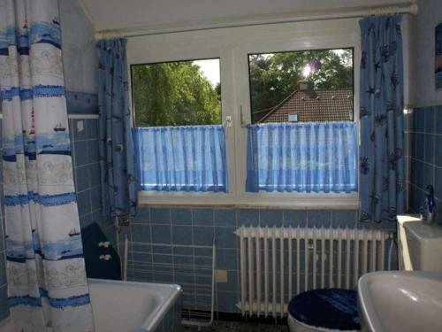 baño con bañera y lavamanos y 2 ventanas en Ferienwohnung Grueßing, 15014, en Leer